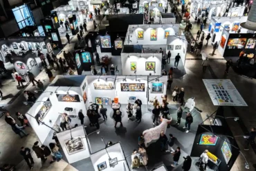 Visiteurs découvrant les œuvres contemporaines à Art Montpellier 2025, sur le thème du voyage.