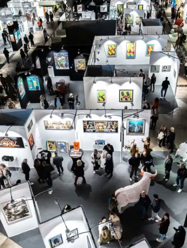 Visiteurs découvrant les œuvres contemporaines à Art Montpellier 2025, sur le thème du voyage.