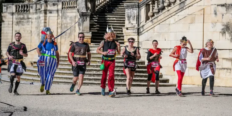 Participants du Nîmes Urban Trail 2026 en pleine course dans une ambiance festive à Nîmes.