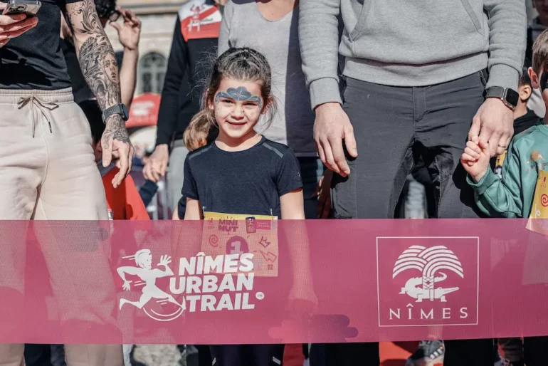Participants du Nîmes Urban Trail 2026 en pleine course dans une ambiance festive à Nîmes.